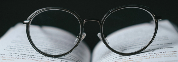 A pair of glasses sitting on a book.