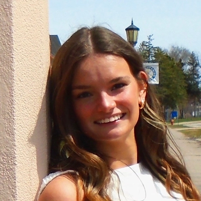 Katelyn smiling, she is outside wearing a white shirt.